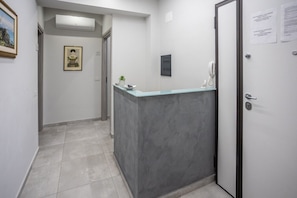 A hallway with a reception desk, a framed picture on the wall, and a door with a sign.