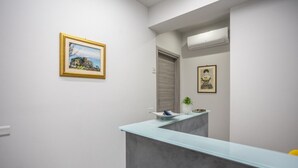 Un área de recepción con mostrador, una obra de arte enmarcada en la pared y una planta en maceta.