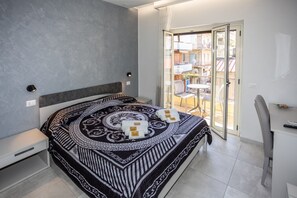 Ein modernes Schlafzimmer mit einem großen Bett, einem Schreibtisch und einem Balkon mit Sitzgelegenheit.