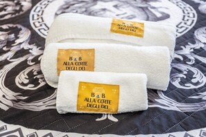 Three folded towels with a label on a patterned bedspread. - At the Court of the Gods - Demeter Room (Tropea)