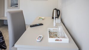 A hotel room with a white desk, a remote control, a kettle, and a tray with items. - At the Court of the Gods - Aphrodite Room (Tropea)