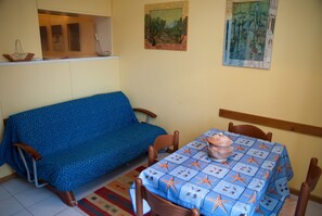 A room with a blue sofa, a table with a starfish tablecloth, and two paintings on the wall. - Surrounded by Pine Forest... Principina a Mare (Principina a Mare)