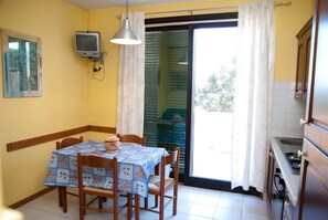 A dining area with a table, chairs, a television, and a kitchen. - Surrounded by Pine Forest... Principina a Mare (Principina a Mare)