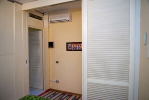 A hallway with a closed door, an air conditioning unit, a framed picture on the wall, and a patterned rug on the floor. - Surrounded by Pine Forest... Principina a Mare (Principina a Mare)
