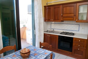 A kitchen with wooden cabinets, a gas stove, and a tiled backsplash.