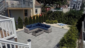 Eine Dachterrasse mit einer Eckcouch, einem Glastisch und einem kleinen Tisch mit Stühlen.
