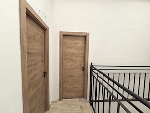 A wooden door with a black handle, a white wall, and a black metal railing. - Collection Las Ventas Apartamento H Cerca de la Plaza de Toros (Madrid)