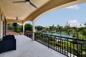 A covered balcony with a view of a water body and greenery.