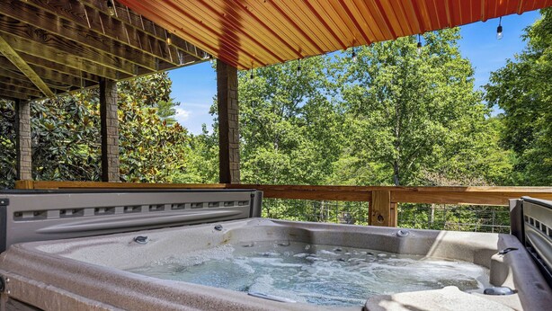 Un jacuzzi bajo una pérgola de madera con vista a árboles.