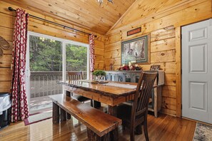 A wooden cabin interior with a dining table, bench, and a framed picture on the wall. - Relax and have Adventure Here! (PIGEON FORGE)