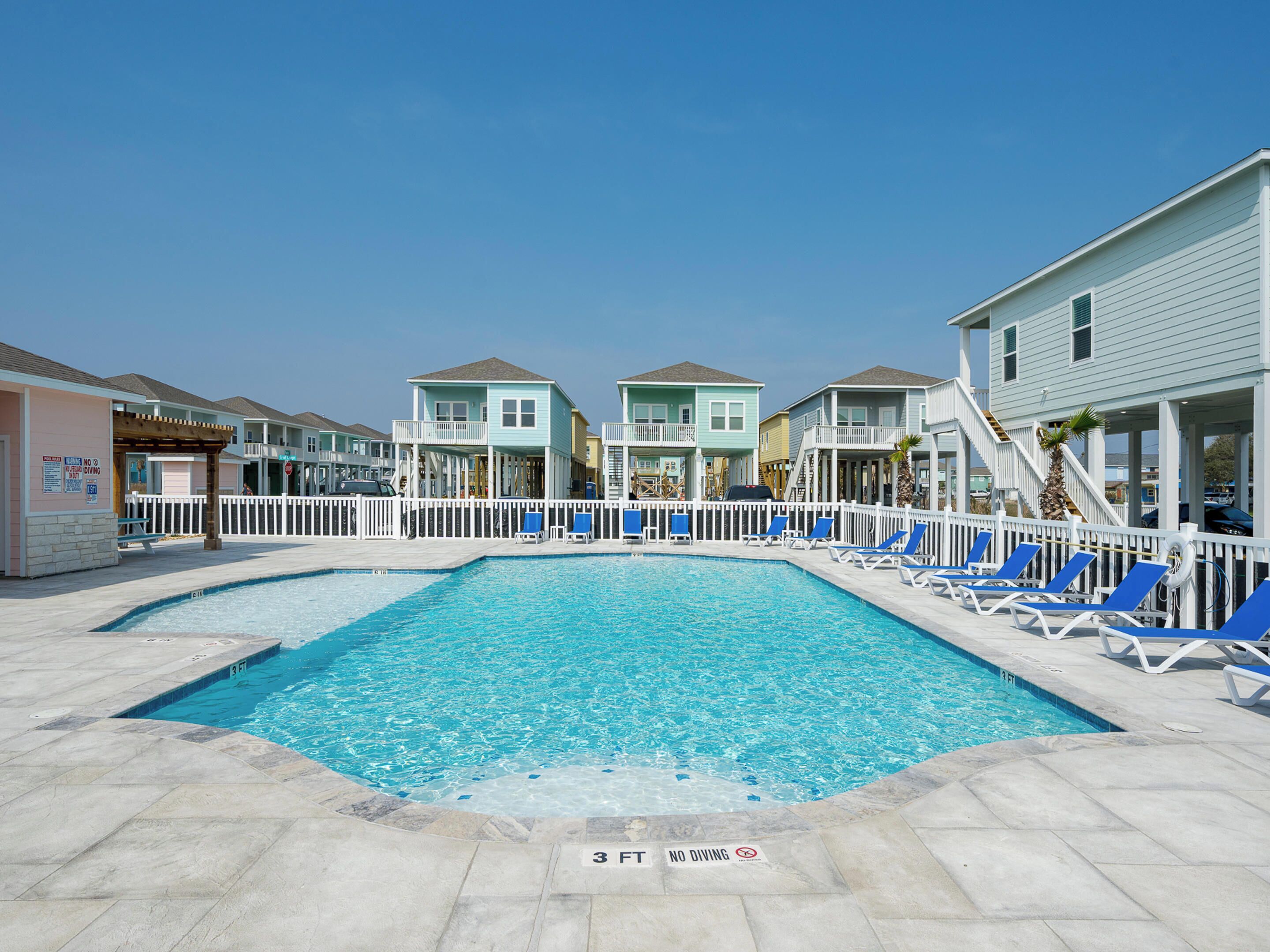 A swimming pool with a 3 FT depth limit and no diving sign, surrounded by beach houses with balconies and a white fence.