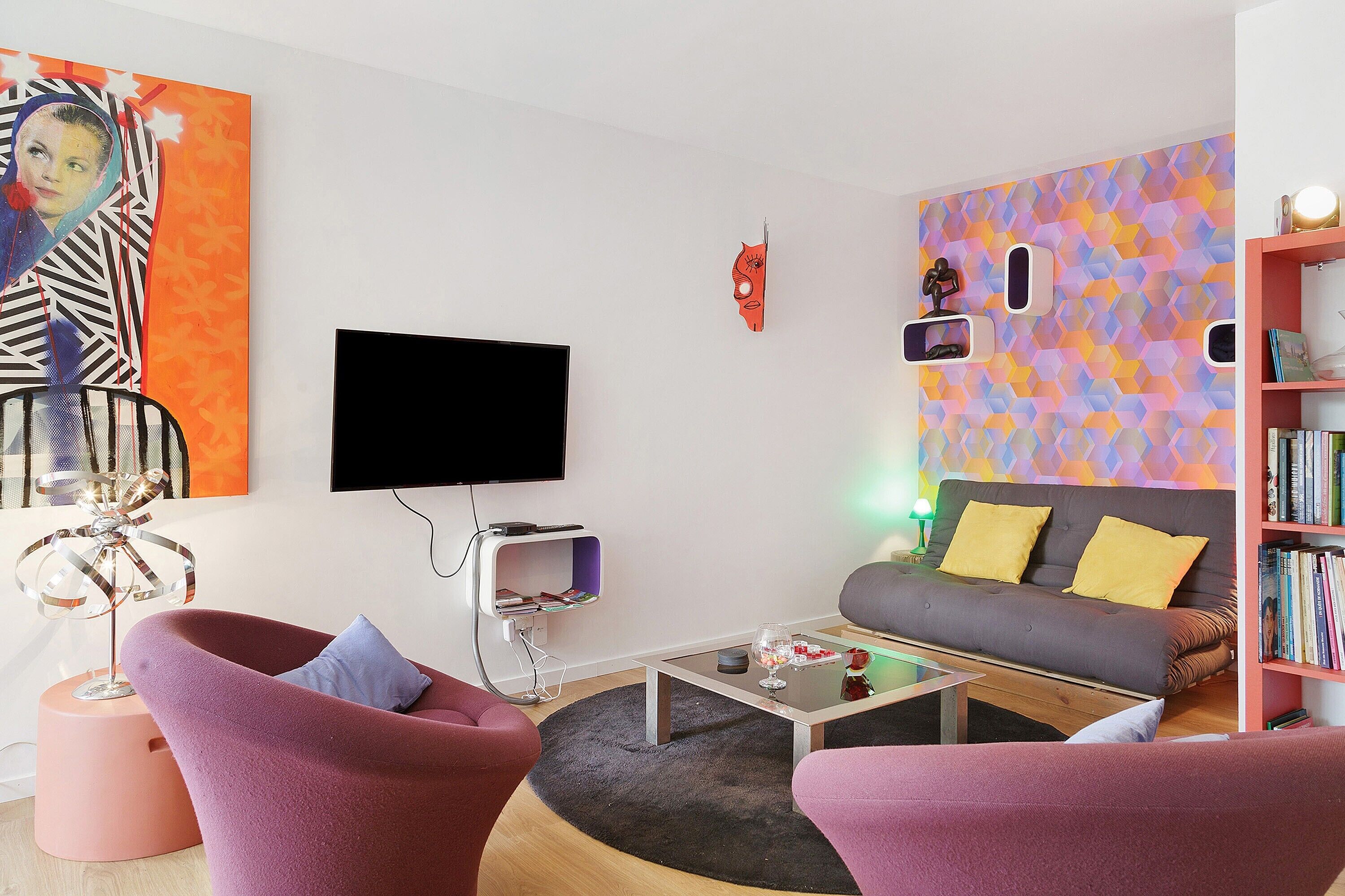A modern living room with a sofa, armchairs, a coffee table, and a bookshelf.