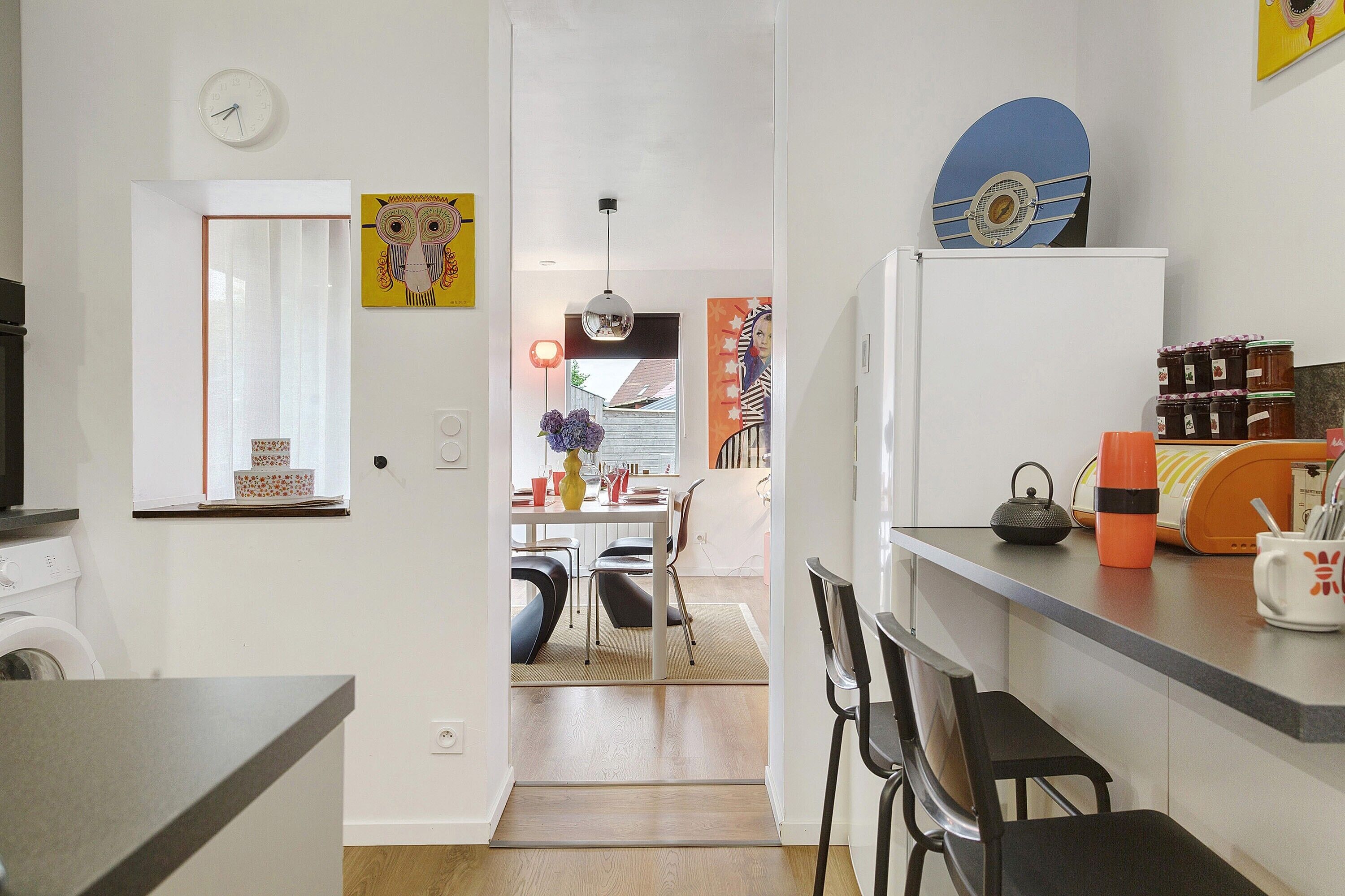 A modern kitchen with a dining area, a washing machine, and a refrigerator.