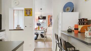 A modern kitchen with a dining area, a washing machine, and a refrigerator.