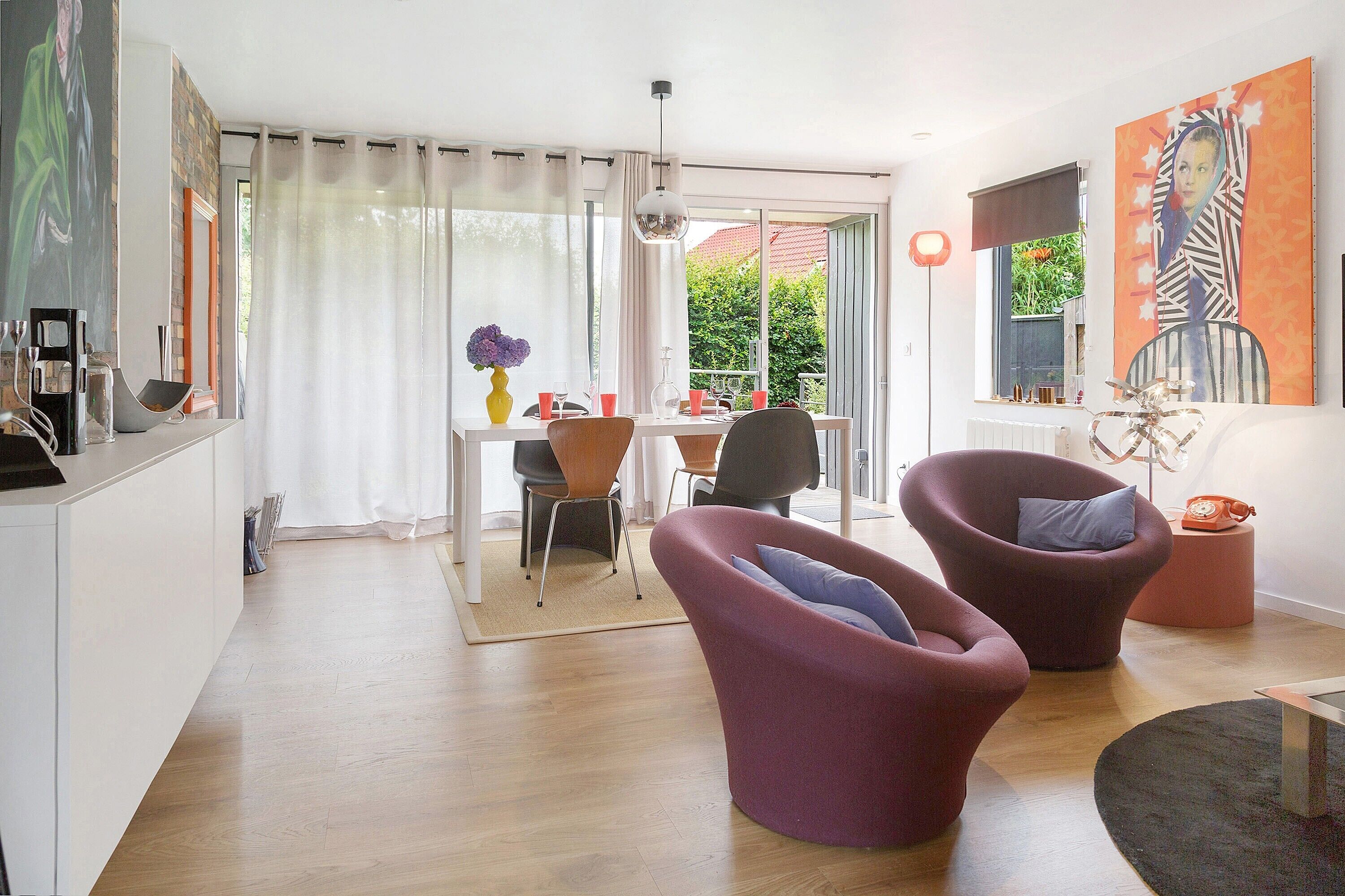 A modern living room with a dining area, a large window with a view, and contemporary furniture.