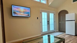 A hallway with a glass-top table, a painting of a sunset, double doors, and a refrigerator. - Petite Palace: Guest home in Louisburg, NC (Louisburg)