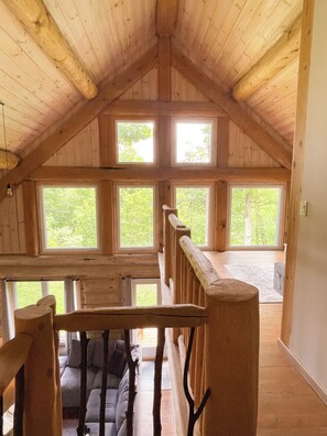 A wooden interior with a sloped ceiling, multiple windows, and a staircase. - Premium log cabin, peaceful cozy retreat in nature, nearby Golf Montebello (Montebello)