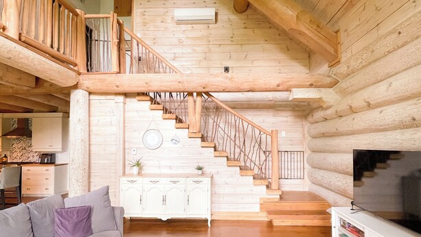 Un vaste espace de vie comprenant un escalier en bois, un canapé, une table basse et un téléviseur.