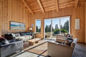 Ein Zimmer mit Holzwänden, einem großen Fenster, einem Gemälde und einem Sofa.
