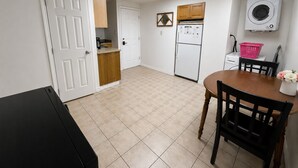 Eine kompakte Küche mit Kühlschrank, Waschmaschine und Essbereich mit Tisch und Stühlen.