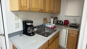 Eine kompakte Küche mit Holzausstattung, einem integrierten Spülbecken, einer Kaffeemaschine und einem Toaster.