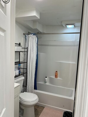 Ein Badezimmer mit Toilette, Dusche und Ablage für Toilettenartikel.