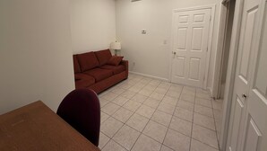 Ein Zimmer mit einem braunen Sofa, einem Esstisch und einer weißen Tür.