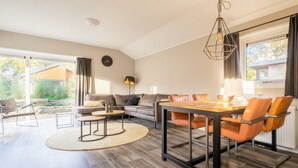 Un salon moderne comprenant un coin repas, un canapé, une table basse et un luminaire suspendu.