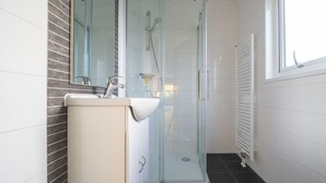 Une salle de bain moderne avec une douche à parois de verre, un lavabo avec un miroir et des toilettes.