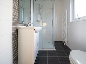 Ein modernes Badezimmer mit einer Duschkabine, einem Waschbecken mit Spiegel und einer Toilette.