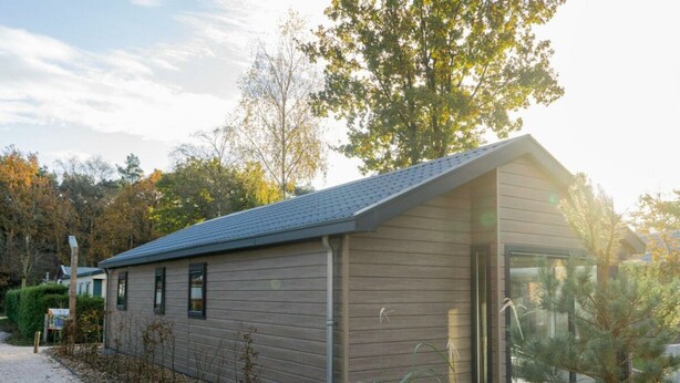 Un bâtiment moderne doté d’un toit en pente, d’une entrée en verre et d’un chemin bordé de gravier.