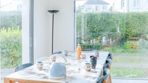 Uma sala de jantar com uma mesa posta para quatro pessoas, uma chaleira e uma garrafa de sumo de laranja.
