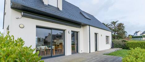 A modern house with a large sliding glass door, a covered patio, and a sloped roof.