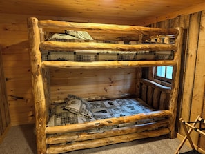 Ein Stockbett mit Holzrahmen, vielen Kissen und einem Fenster.