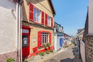 A narrow street with buildings featuring red shutters and a sign for 'Dole Vita.'