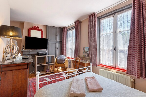 A hotel room with a bed, a desk, a chair, a television, and a window with curtains.