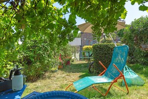 A garden with a blue chair, a wheelbarrow, and potted plants.