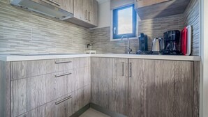 Une cuisine moderne avec des meubles en bois, une hotte de cuisinière en acier inoxydable, une fenêtre et une machine à café.