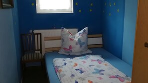 Ein Schlafzimmer mit einem Einzelbett, einem Sessel, einem Heizkörper und einem Fenster mit Sterndekoration.