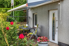 Ein Patio mit Tisch und Stühlen, einer Tür und einem Fenster.