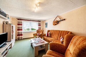 Ein gemütliches Wohnzimmer mit einer Couch, einem Couchtisch und einer Gitarre an der Wand.