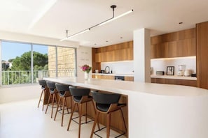 Une cuisine moderne dotée d’un grand îlot central, de tabourets de bar et de meubles de rangement en bois.