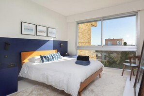 Ein Schlafzimmer mit einem großen Bett, einem Fenster mit Blick und gerahmten Bildern an der Wand.