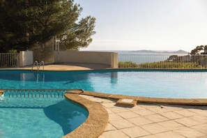 Ein Pool mit geschwungener Kante, einer Metallleiter und Blick auf das Meer.