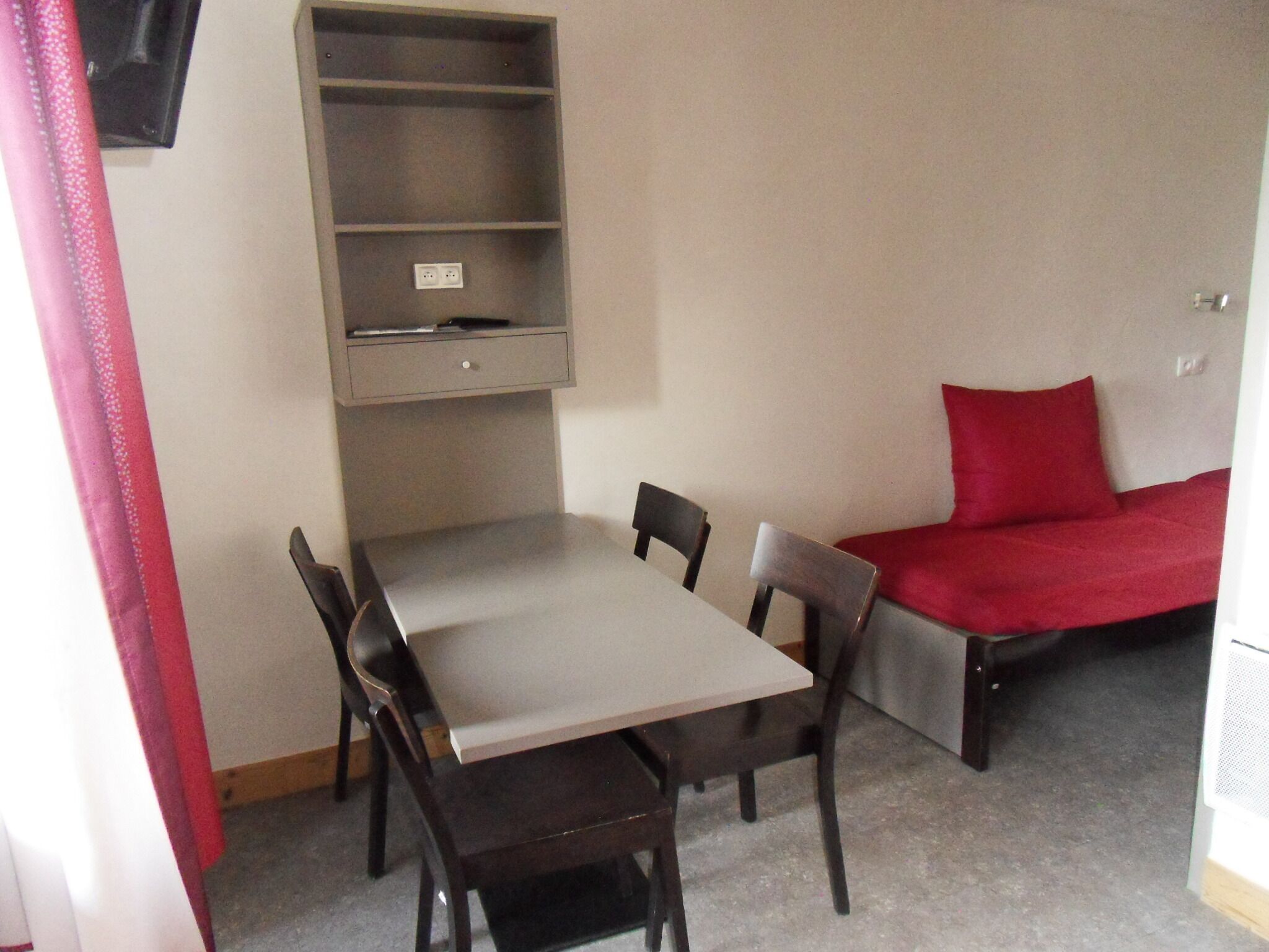 A small room with a bed, a desk, and two chairs.