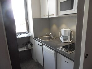 A compact kitchen with a dishwasher, a coffee maker, and a microwave. - travelski home select - Résidence 3000 - Studio 4 personnes 326 (La Plagne)