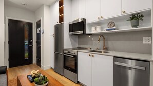 A modern kitchen with stainless steel appliances, a built-in oven, a dishwasher, and a sink with a gold faucet. - Charming studio in Seattle perfect for your city getaway (Seattle)