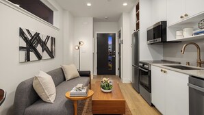 A modern kitchen with stainless steel appliances, a wooden coffee table, and a grey sofa with cushions. - Charming studio in Seattle perfect for your city getaway (Seattle)