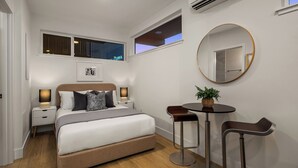 A bedroom with a bed, bedside tables, a round mirror, a small table with chairs, and a window. - Charming studio in Seattle perfect for your city getaway (Seattle)