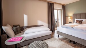 A hotel room with a bed, a sofa, a small table, and a view of the outside.
